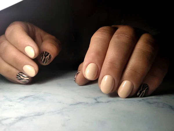 Camouflage gel Polish on short round nails. Beige coating with striped design. Tiger and leopard design.