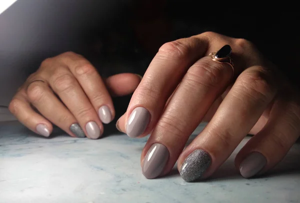 Clean manicure with a coating of dirty asphalt color. Grey-brown gel polish with glitter design