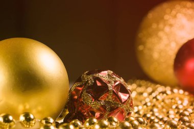 Noel oyuncakları altın ve kırmızı, masada altın boncuklar. Altın desenli kırmızı top. Sıcak renklerde Noel ağacı süslemeleri olan yeni yıl görüntüleri