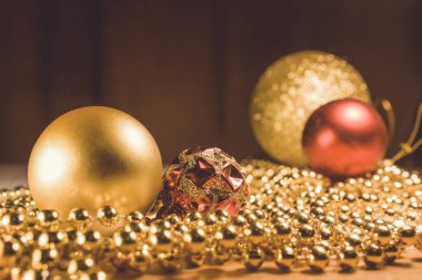 Noel oyuncakları altın ve kırmızı, masada altın boncuklar. Altın desenli kırmızı top. Sıcak renklerde Noel ağacı süslemeleri olan yeni yıl görüntüleri