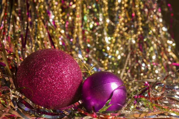 Two red Christmas balls on shiny tinsel. Two Christmas toys of the same color and different sizes. Big shiny red ball and little purple for Christmas tree