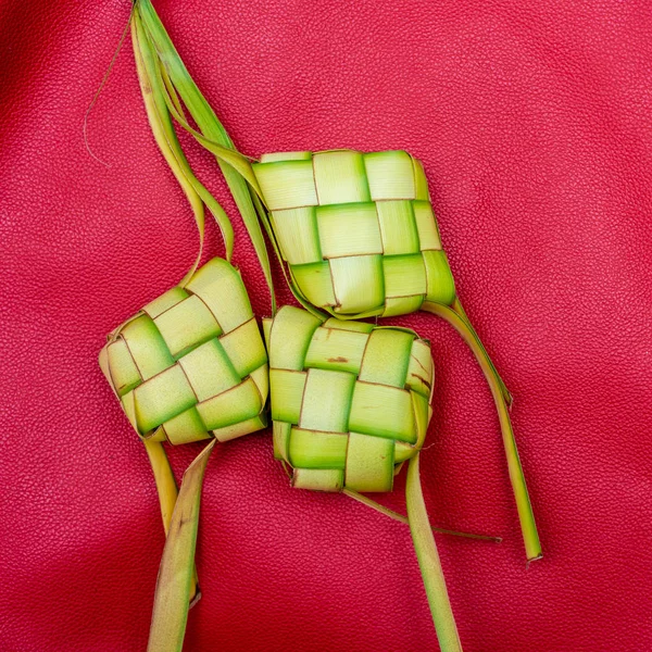 Ketupat woreczki na czerwonym tle. Ketupat jest rodzajem dumpli — Zdjęcie stockowe