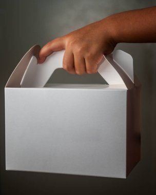 Boş beyaz bir pasta kutusu tutan çocuk.