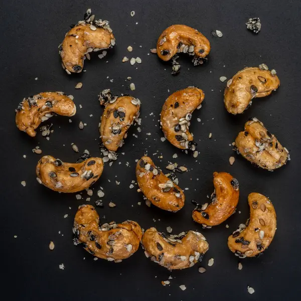 Sesam gecoate cashewnoten. Geïsoleerd op zwarte achtergrond — Stockfoto