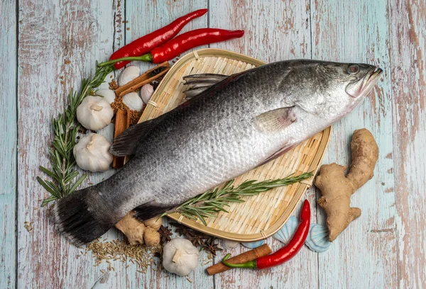 Fresh Sea Bass on rattan plate and wooden background — Stock Photo, Image