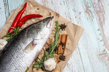 Taze madde ile çevrili ahşap masada Taze Ham Levrek