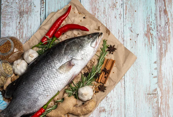 Fresh Raw Sea Bass on wooden table surrounded by fresh ingredien — Stock Photo, Image