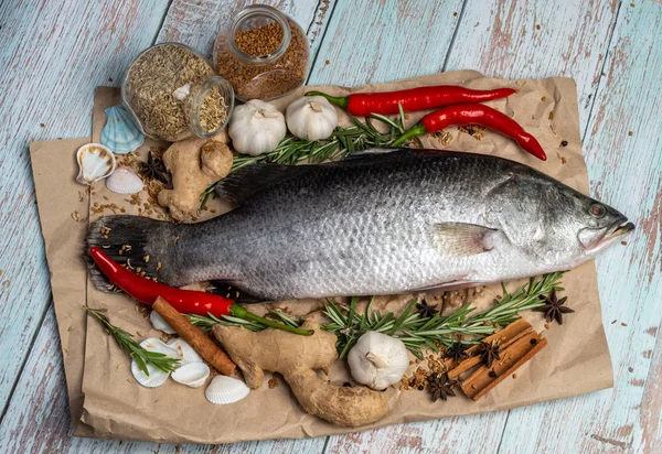 Fresh Raw Sea Bass on wooden table surrounded by fresh ingredien — Stock Photo, Image