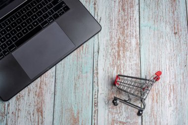 Ahşap masada laptop ve alışveriş sepeti. Online alışveriş cONCEP