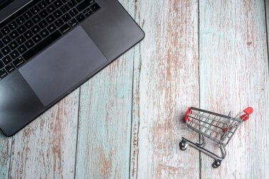 Ahşap masada laptop ve alışveriş sepeti. Online alışveriş cONCEP