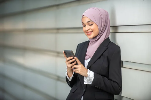 Genç Kadın Müslüman Girişimci akıllı telefonuna bakıyor. Şal