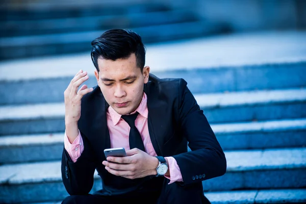 Stressed and angry asian businessman  looking at smartphone scre