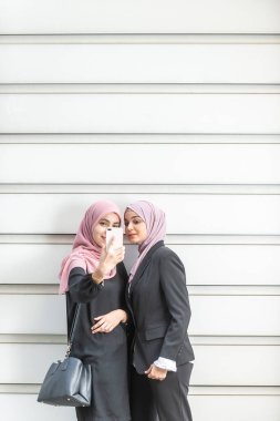 Asyalı Müslüman kızlar selfie çekiyor. Dış mekan ayarı.