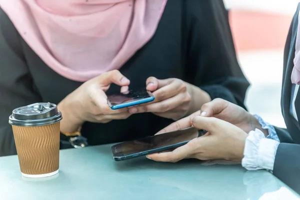 Müslüman İş kadınları kahveleri sırasında akıllı telefonlarıyla b
