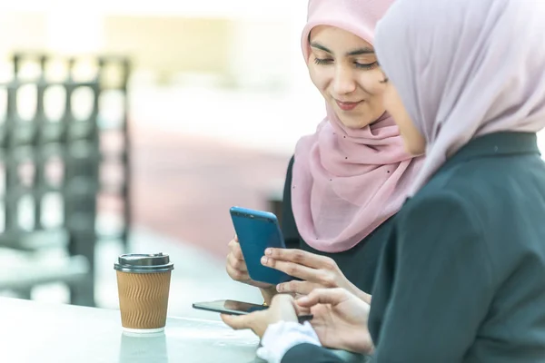 Müslüman İş kadınları kahveleri sırasında akıllı telefonlarıyla b