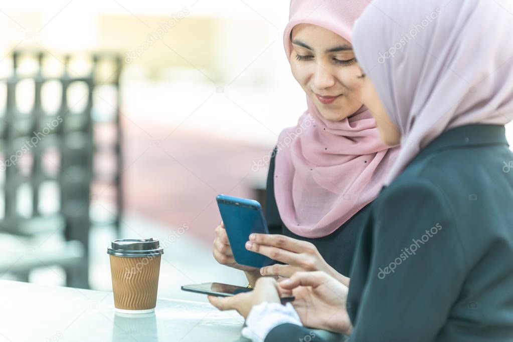 Muslim Businesswomen with their smartphone during their coffee b