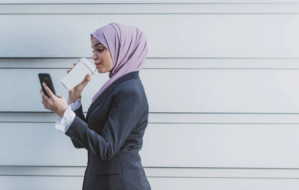 Trabajadora musulmana con su smartphone durante su pausa para el café — Foto de Stock