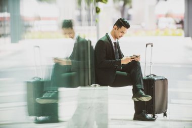 İş Seyahati Taksi Bekliyor. Akıllı telefonuyla oynuyor