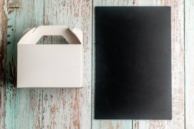 Boş karatahta tahtası ve tahta arka planda paket kutusu. Menü c