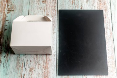Boş karatahta tahtası ve tahta arka planda paket kutusu. Menü c