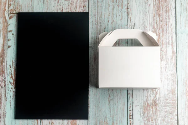 Blank Black board and take away box on wooden background. Menu c