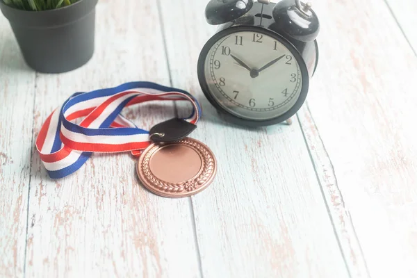 Medaglia sportiva e sveglia su fondo in legno. Tempo di vincita c — Foto Stock