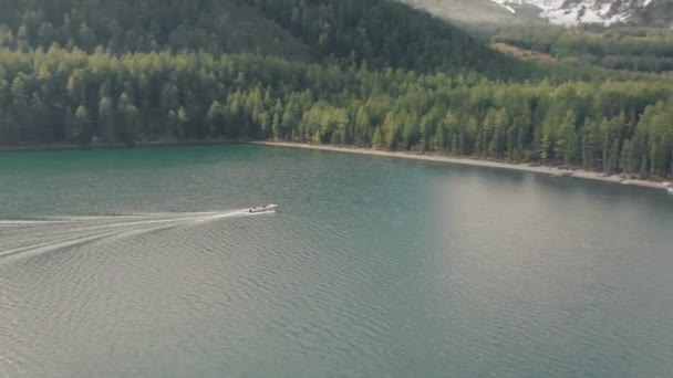 Båten seglar genom en fjällsjö. Filmdrönare flyger över en sjö i bergen. — Stockvideo