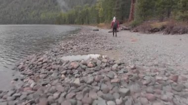 Dağ gölünün kıyısında genç, bekar bir kadın. İHA atışı.
