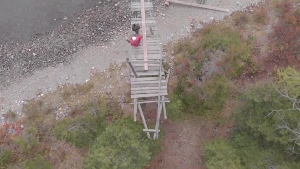 Jonge vrouw zit op een oude pier aan de oever van het bergmeer en drinkt — Stockvideo