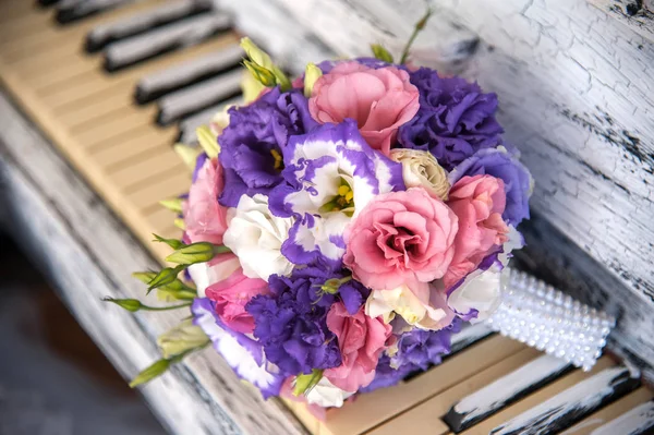 Rhinestones bir kolu ile piyano üzerinde beyaz, pembe, leylak ve mor çiçekler, gül ve eustoma kurdeleler ile bağlı gelin düğün buketi