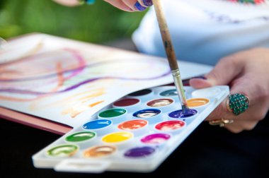 doğada parlak suluboya boyabir resim çizim, boya ve fırça tutan bir adamın yakın çekim