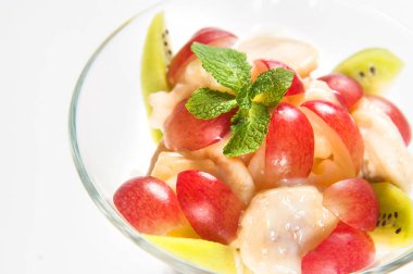 Diyet Fruit SaladKiwi, üzümler, muz, yoğurtla tatlandırılmış ve nane filizi ile süslenmiş..