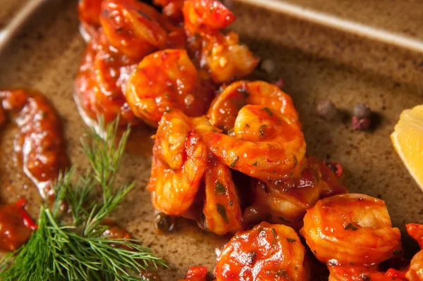 Domates soslu karides, otlu ve limonlu kahverengi tabak. Restoran yemeği. Yakın plan. Yiyecekler. Deniz ürünleri. Akdeniz menüsü