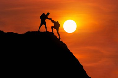 siluet dağcı arkadaşı birlikte yüksek cliff dağa tırmanmaya yardım eli verir. ekip çalışması başarı kavramı.