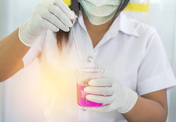 scientist woman dropping pink chemical liquid with test tube glass  for carrying research chemistry liquid in science laboratory