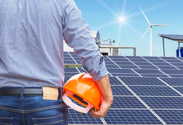 太陽電池と風力発電機ハイブリッド発電システム ステーションでの発電と黄色いヘルメットを保持しているエンジニアのスタンド — ストック写真