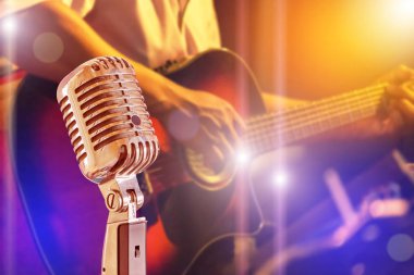 Gece konseri arka planda orkestra akustik gitar oynarken müzisyen ile Retro mikrofon yakın
