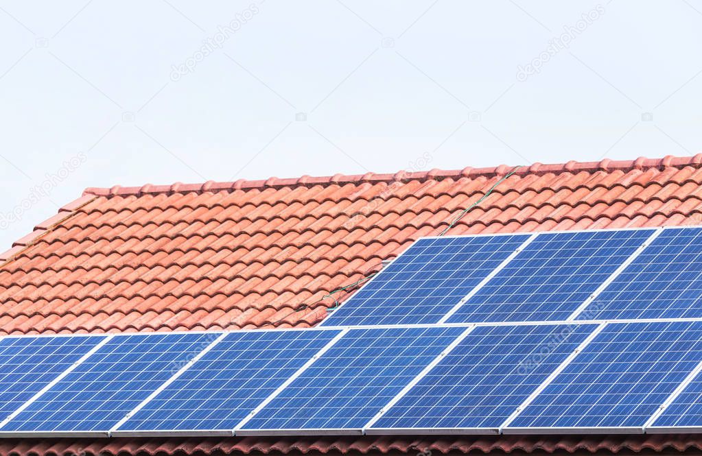 Close up rows array of polycrystalline silicon solar cells or photovoltaics installing on red concrete tiles roof house turn up skyward absorb the sunlight from the sun 