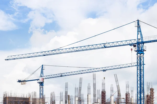 big blue cranes in building construction site on blue sky