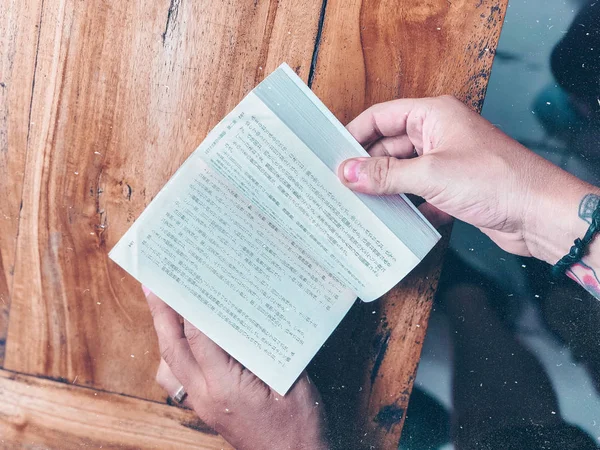 Man hands flipping pages Asian book