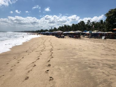 Mavi gökyüzü ve küçük bulutlar ve güneşli bir günde beyaz kum üzerinde adımlar ile Güzel okyanus Manzara, Bali Kuta