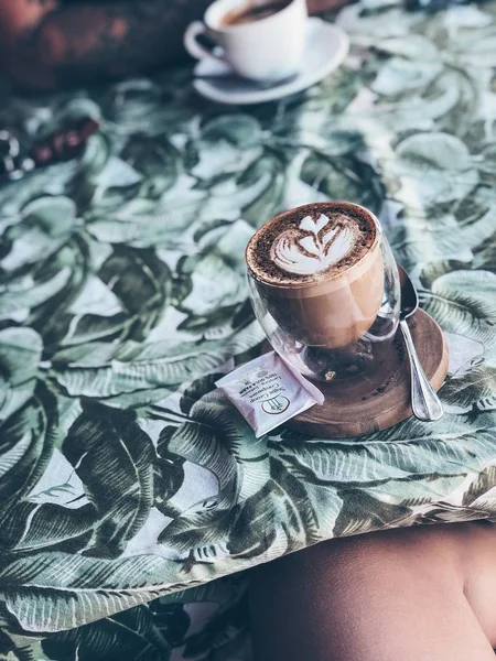 Glas Cappuccino auf grünem Tisch mit Dschungel, warmer Ton, — Stockfoto