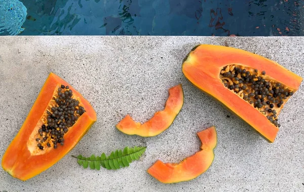 Summer composition with papaya  and leaves on grey background near the pool — Stock Photo, Image