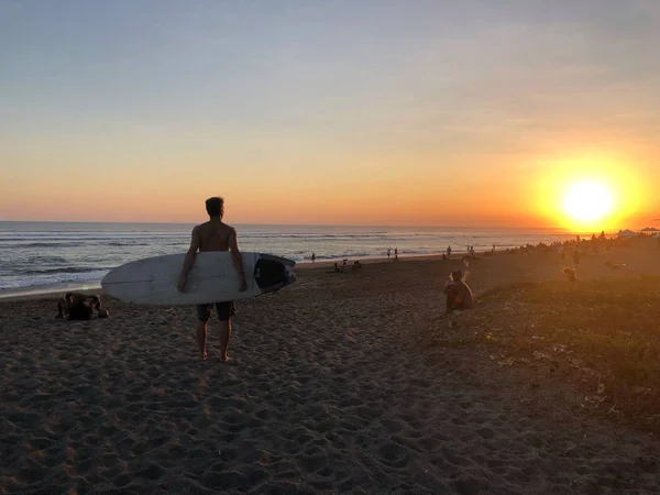 Mutlu sörfçü Gün batımında, Bali sahilde sörf tahtaları ile ayakta.