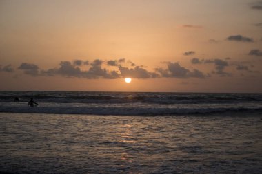 bulutlu gökyüzü günbatımı sırasında altında sahilde sörf dalgaların doğal görünümü