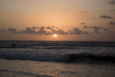 bulutlu gökyüzü günbatımı sırasında altında sahilde sörf dalgaların doğal görünümü