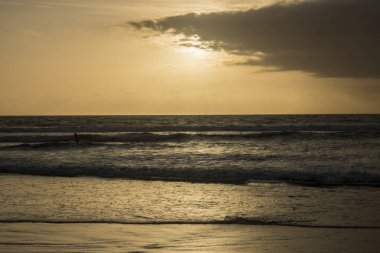 bulutlu gökyüzü günbatımı sırasında altında sahilde sörf dalgaların doğal görünümü