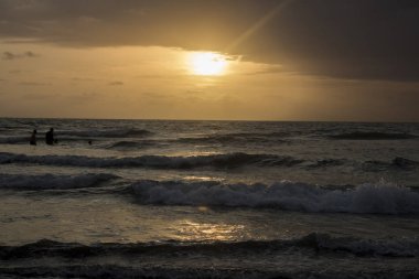 bulutlu gökyüzü günbatımı sırasında altında sahilde sörf dalgaların doğal görünümü