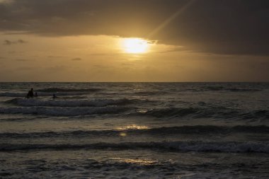 bulutlu gökyüzü günbatımı sırasında altında sahilde sörf dalgaların doğal görünümü