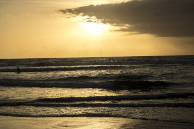 bulutlu gökyüzü günbatımı sırasında altında sahilde sörf dalgaların doğal görünümü